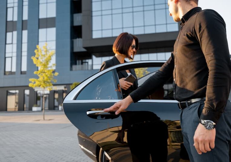 Chauffeur helps an elegant business woman gets in car